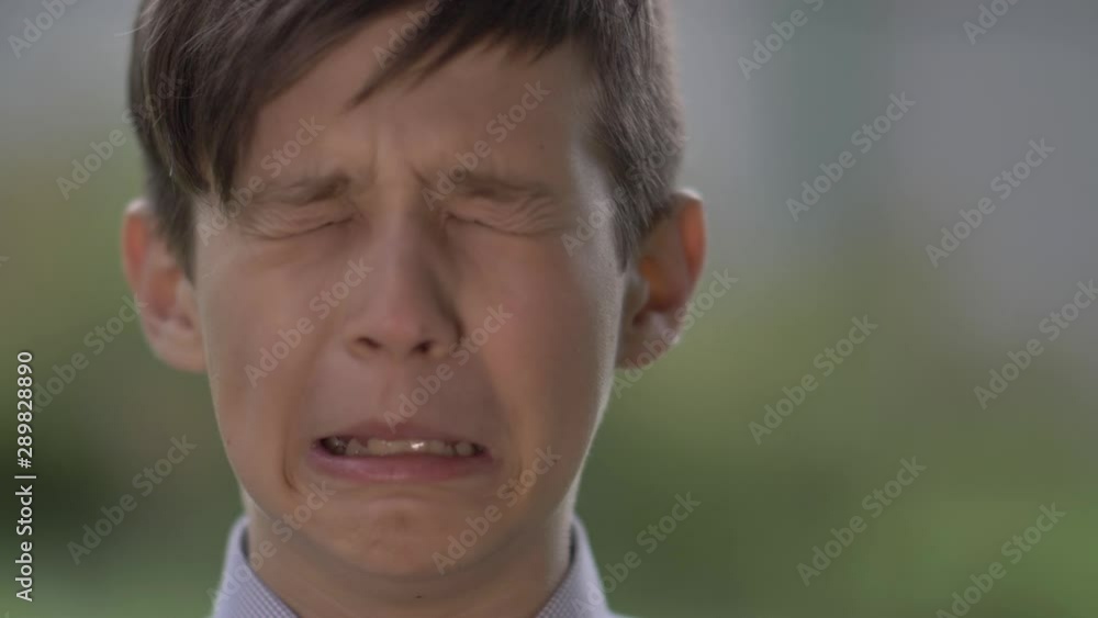 offended boy looks into the camera and crying, close up offended boy looks into the camera and crying, close up