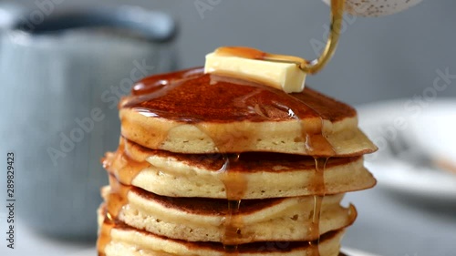 Pancakes with butter and maple syrup. Pouring syrup on stack of fluffy buttermilk pancakes, american style breakfast