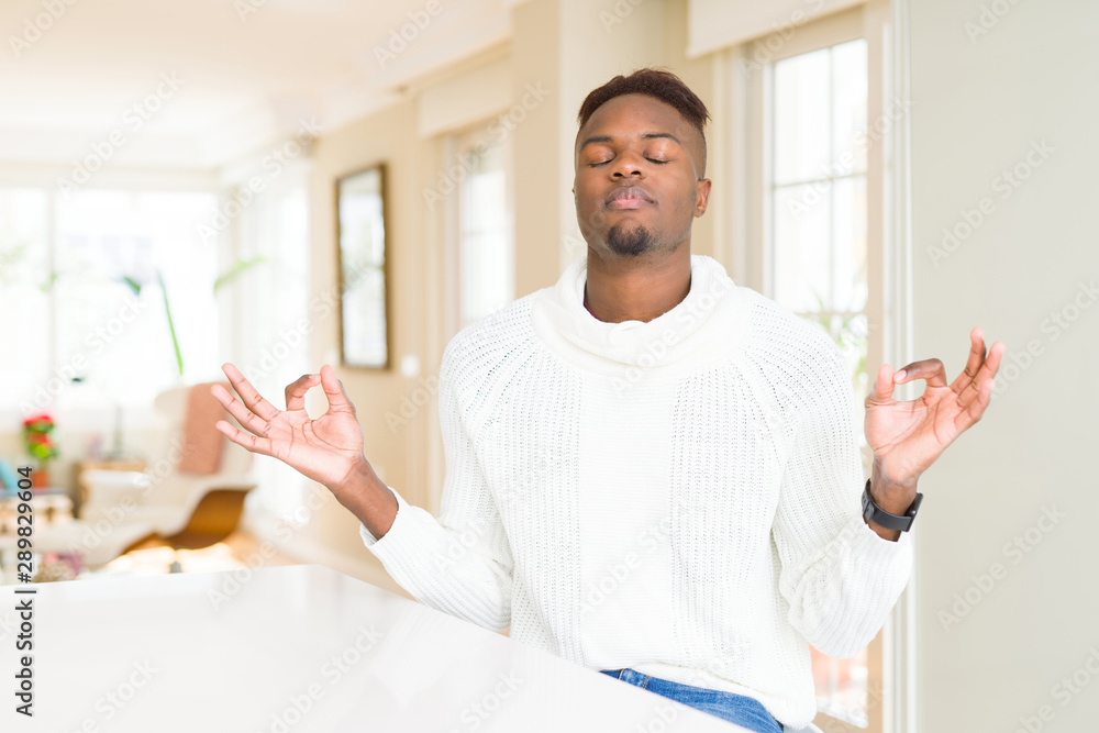 Handsome african american man on white table relax and smiling with eyes closed doing meditation gesture with fingers. Yoga concept. Handsome african american man on white table relax and smiling with eyes closed doing meditation gesture with fingers. Yoga concept.