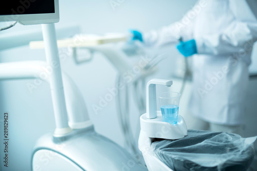 Dentist in sterile gloves standing near dental equipment