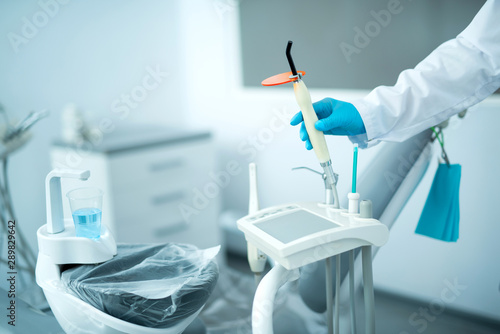 Dentist in sterile gloves holding special dental equipment