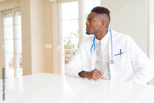 African american doctor man at the clinic looking to side, relax profile pose with natural face with confident smile.