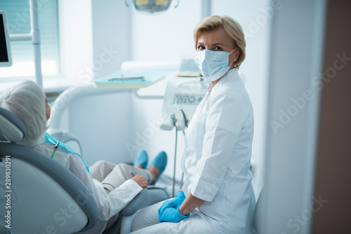 Female dentist with her mature gray-haired patient