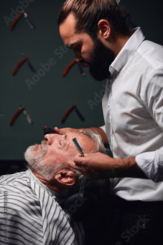 barber preparing client's face for shaving, trimming. close up side view photo