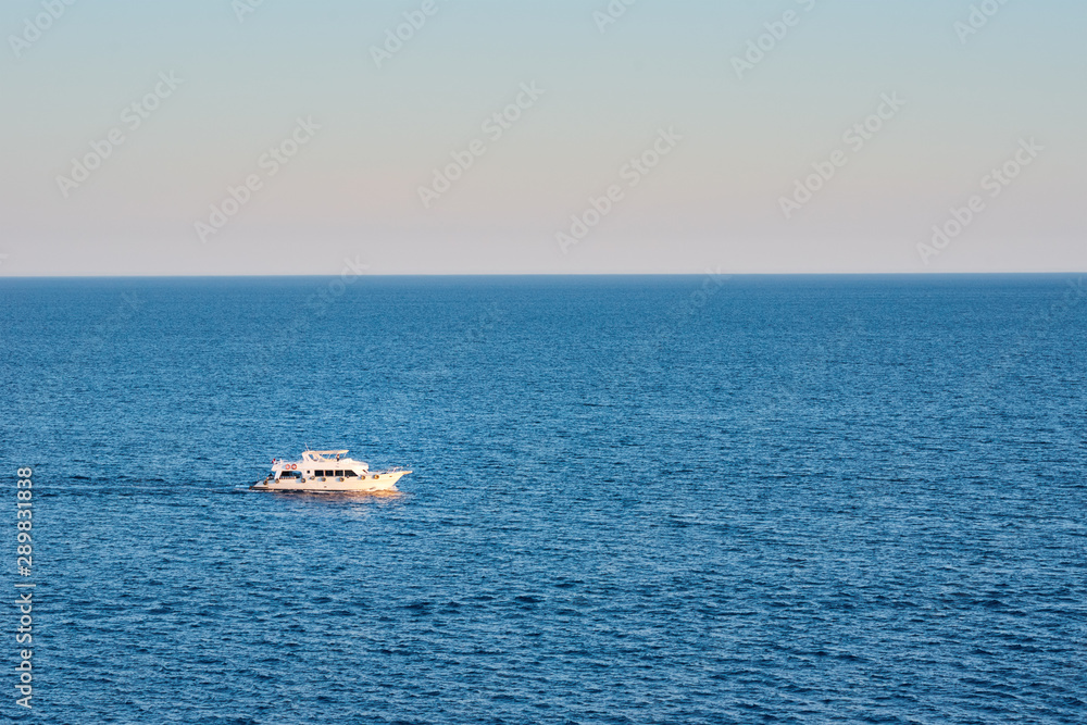 White ship in sea or ocean against sunset