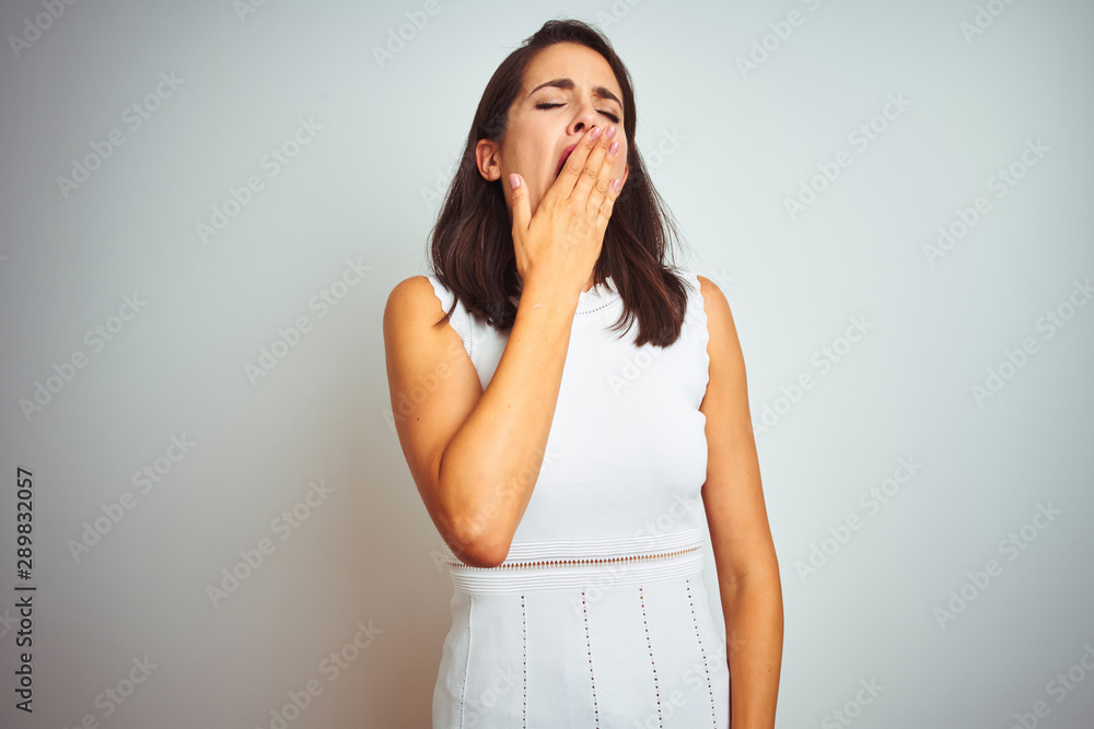 Young beautiful woman wearing dress standing over white isolated background bored yawning tired covering mouth with hand. Restless and sleepiness. Young beautiful woman wearing dress standing over white isolated background bored yawning tired covering mouth with hand. Restless and sleepiness.