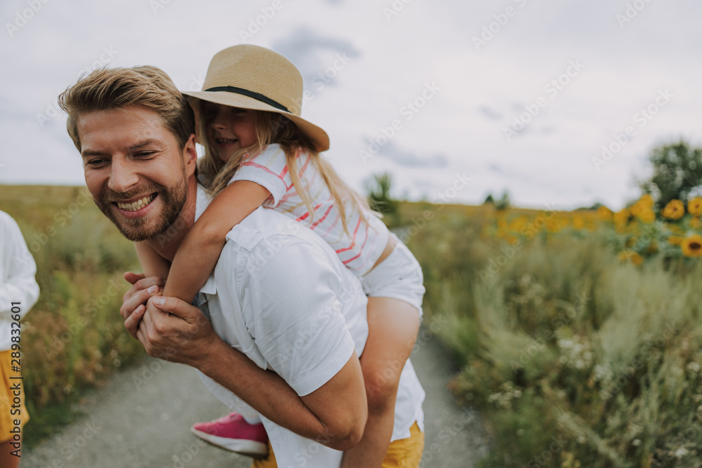 Small joyful daughter spending time with her dad near field