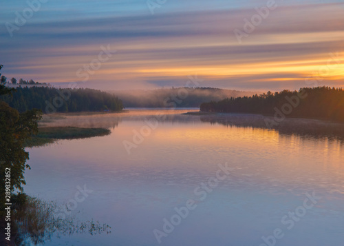 Long Exposure of Sunset at the Paijanne lake. Beautiful scape with sunrise sky, pine forest and water. Lake Paijanne, Finland.