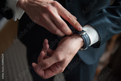 Men in suite closing the hand watch belt