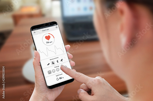 Heart rate and oxygen measure concept. Woman use phone and sensor in office to monitoring health.