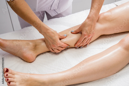 Beautiful young woman enjoying legs massage with oil in spa salon. Cosmetology