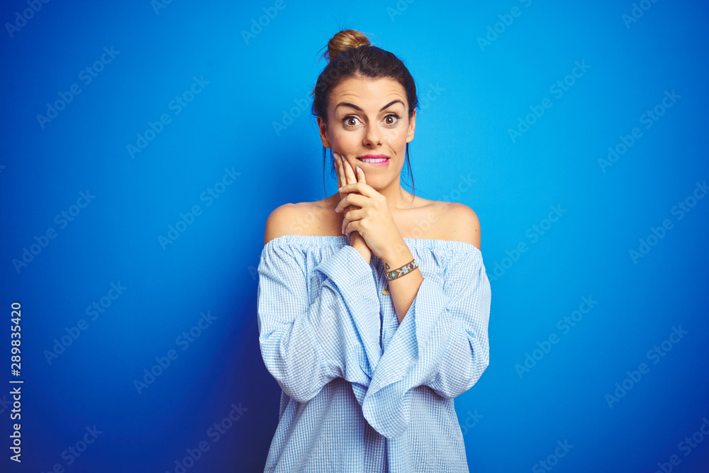 Young beautiful woman wearing bun hairstyle over blue isolated background laughing nervous and excited with hands on chin looking to the side Young beautiful woman wearing bun hairstyle over blue isolated background laughing nervous and excited with hands on chin looking to the side