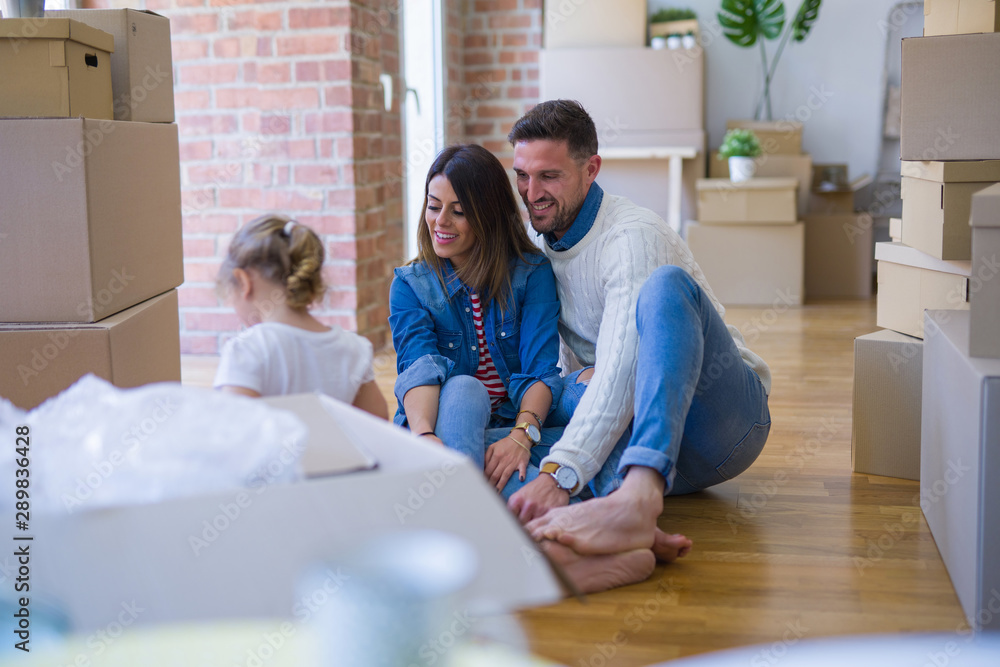 Beautiful family sitting on the floor playing with his kid at new home around cardboard boxes Beautiful family sitting on the floor playing with his kid at new home around cardboard boxes