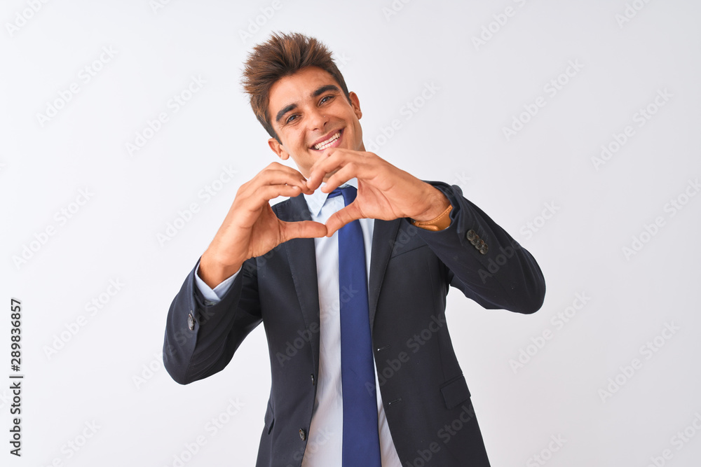 Young handsome businessman wearing suit standing over isolated white background smiling in love doing heart symbol shape with hands. Romantic concept.
