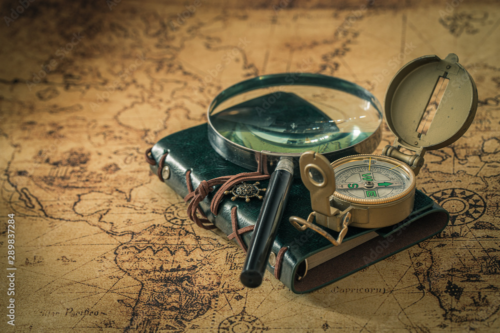 old map with compass, notebook and magnifying glass. The concept of searching for interesting places or treasures around the world. - obrazy, fototapety, plakaty 