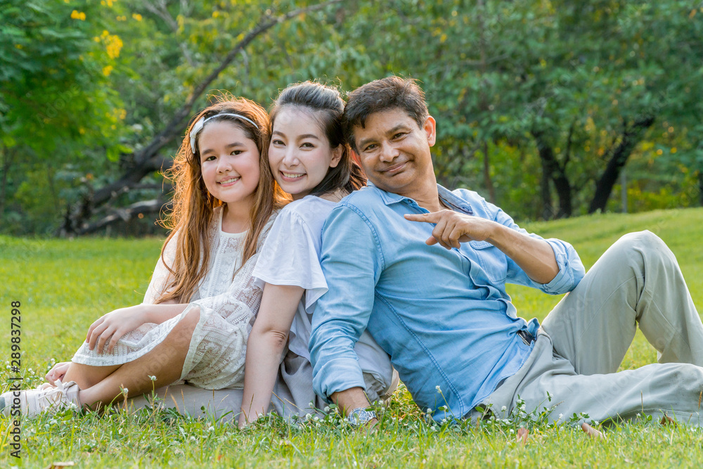 Happy Asian family portrait sitting and relaxing together in the park. Happy Asian family portrait sitting and relaxing together in the park.