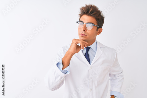Young handsome sciencist man wearing glasses and coat over isolated white background with hand on chin thinking about question, pensive expression. Smiling with thoughtful face. Doubt concept.