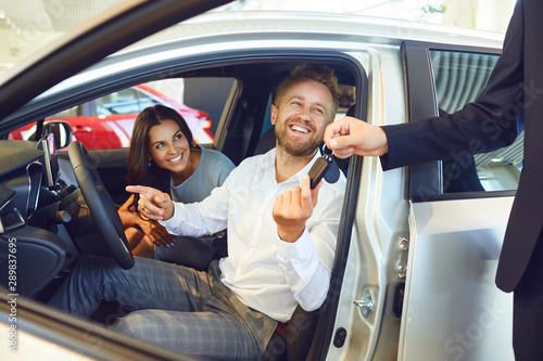 Quadro em tela A happy couple bought a new car at a car showroom.