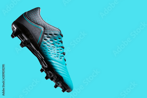 football boots hovering in the air, as if hitting the ball, concept, sports shoes, on a turquoise background