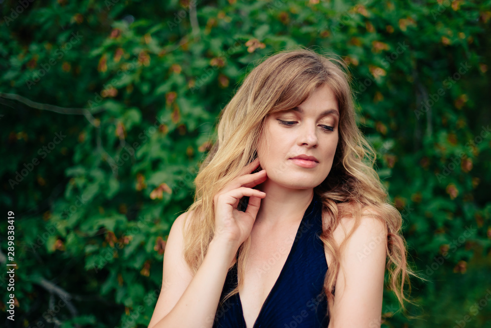 beautiful girl in a black dress outdoors in a park on a background of greenery beautiful girl in a black dress outdoors in a park on a background of greenery