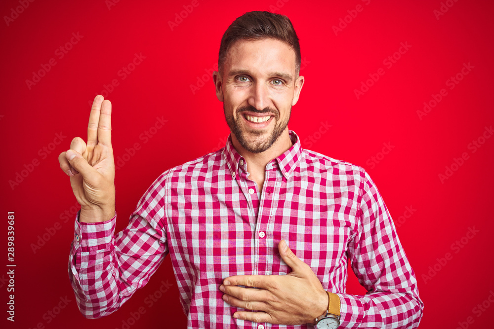 Young handsome man over red isolated background smiling swearing with hand on chest and fingers up, making a loyalty promise oath Young handsome man over red isolated background smiling swearing with hand on chest and fingers up, making a loyalty promise oath