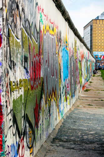 part of the Berlin wall full of graffiti and taken from a very lateral angle at the East Side Gallery
