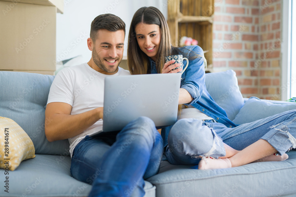 Young couple moving to a new home relaxing sitting on the sofa using computer laptop, smiling happy for moving to new apartment Young couple moving to a new home relaxing sitting on the sofa using computer laptop, smiling happy for moving to new apartment
