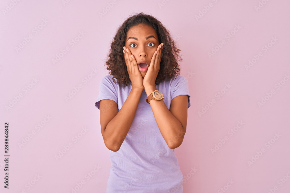 Young brazilian woman wearing t-shirt standing over isolated pink background afraid and shocked, surprise and amazed expression with hands on face Young brazilian woman wearing t-shirt standing over isolated pink background afraid and shocked, surprise and amazed expression with hands on face
