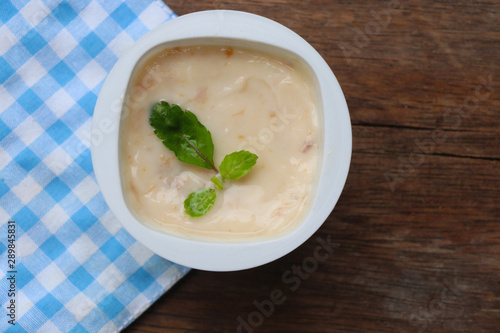 Prune yogurt with pepper mint topping good healthy and delicious in plastic glass on wood table background