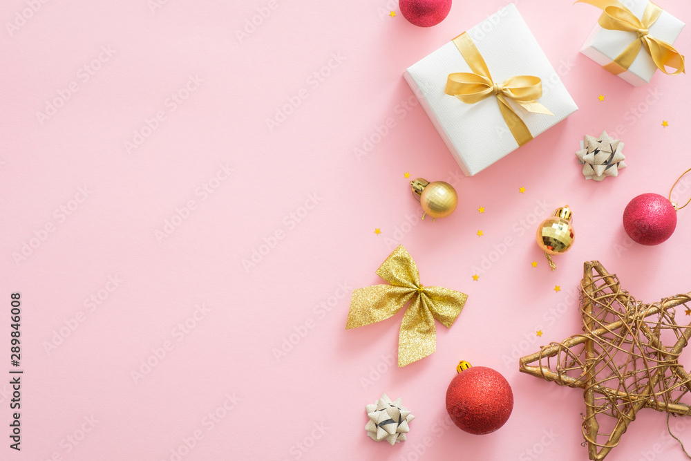 Flatlay Christmas holidays composition on pastel pink background with copy space. Top view Xmas decorations, red and golden balls, gift box, star, bow. Christmas greeting card mockup, banner template
