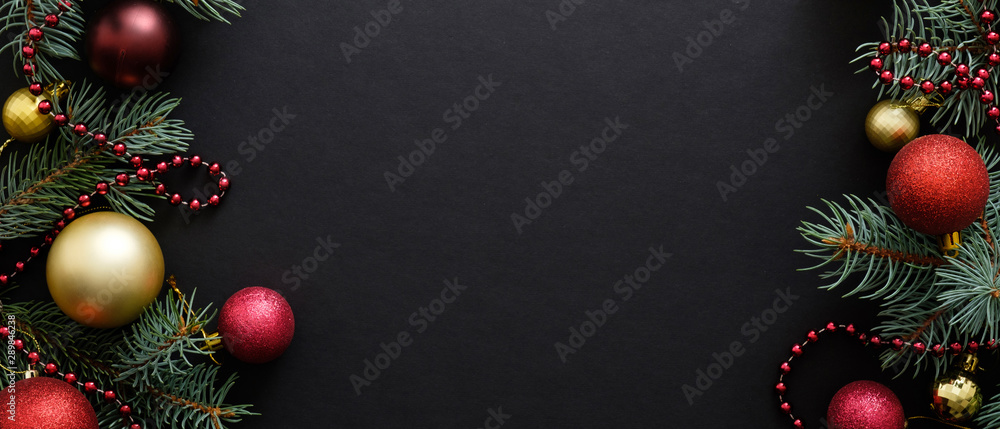 Christmas banner. Black Xmas background with fir tree branches, golden and red balls, garland. Christmas frame, greeting card template, web banner mockup. Flat lay, top view, copy space Christmas banner. Black Xmas background with fir tree branches, golden and red balls, garland. Christmas frame, greeting card template, web banner mockup. Flat lay, top view, copy space