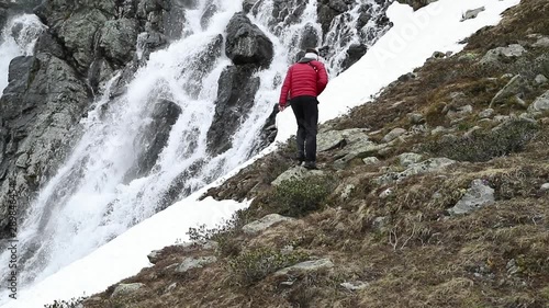 Man walk to waterfall near Susch pass near Davos in Switzerland to take photo. Filmed in slow motion. photo