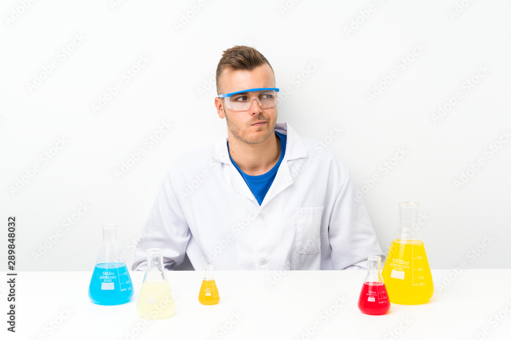 Young scientific with lots of laboratory flask standing and looking to the side Young scientific with lots of laboratory flask standing and looking to the side