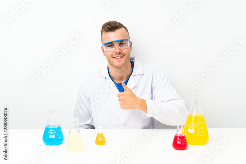 Young scientific with lots of laboratory flask giving a thumbs up gesture