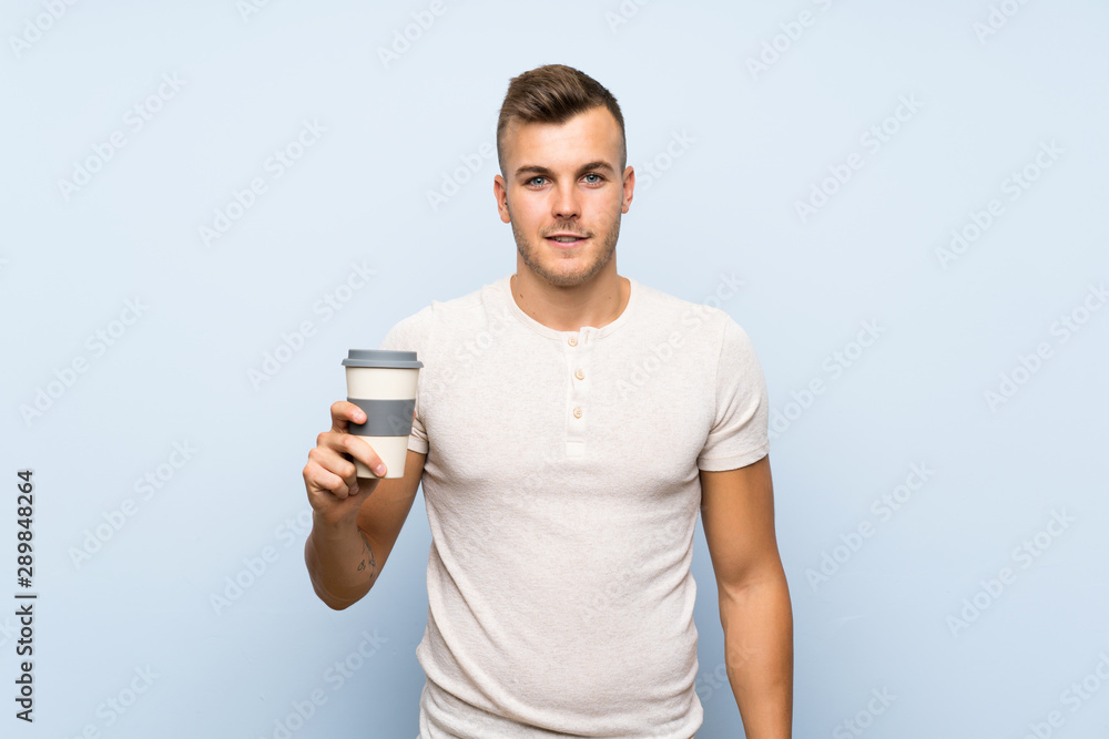 Young handsome blonde man over isolated blue background holding hot cup of coffee Young handsome blonde man over isolated blue background holding hot cup of coffee