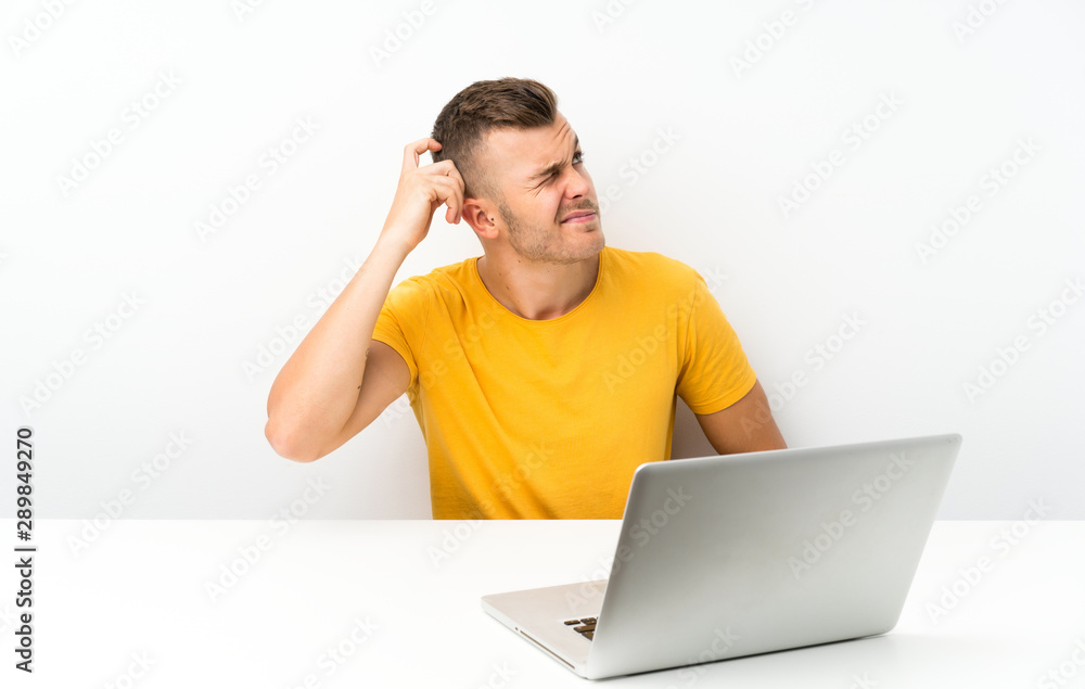 Young blonde man in a table with a laptop having doubts and with confuse face expression Young blonde man in a table with a laptop having doubts and with confuse face expression
