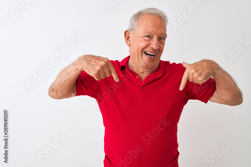 Senior grey-haired man wearing red polo standing over isolated white background looking confident with smile on face, pointing oneself with fingers proud and happy.