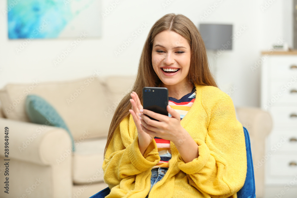 Happy young woman playing online lottery using smartphone at home Happy young woman playing online lottery using smartphone at home