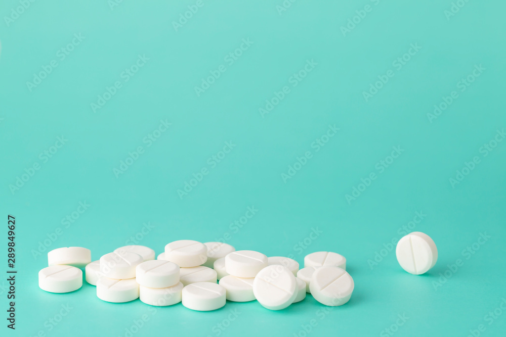 White round pills close-up on a colored background White round pills close-up on a colored background