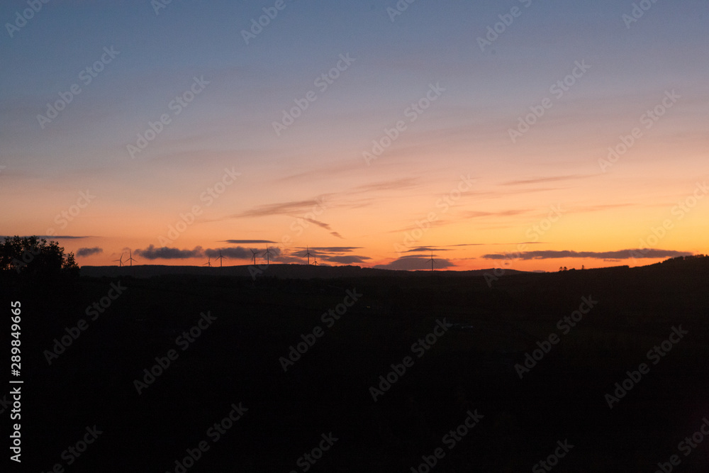 Orange sunset in late summer in Ireland wind turbines visible on horizon Orange sunset in late summer in Ireland wind turbines visible on horizon