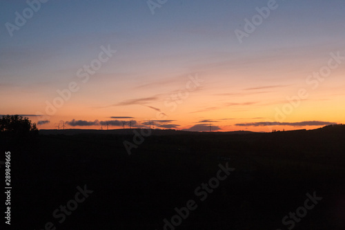 Orange sunset in late summer in Ireland wind turbines visible on horizon 