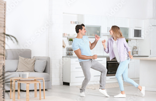 Beautiful young couple dancing in kitchen at home