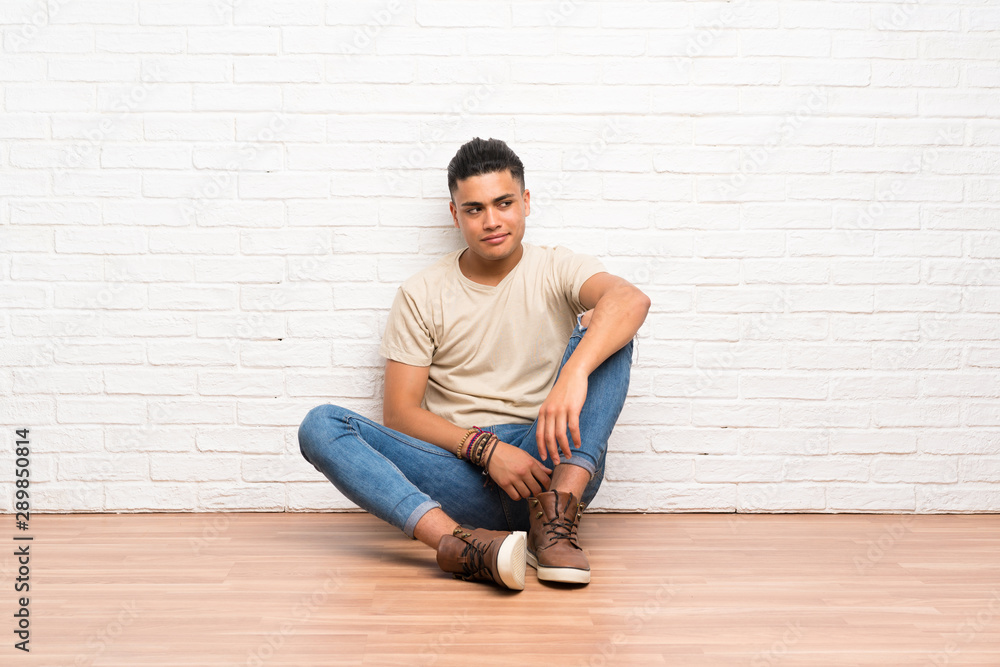 Young man sitting on the floor standing and looking to the side