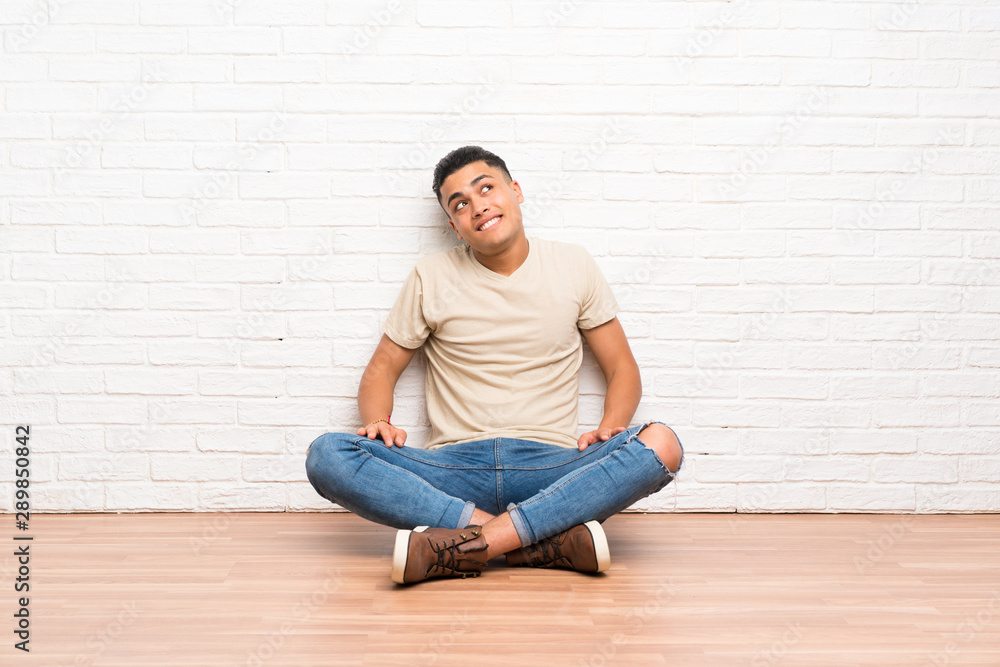 Young man sitting on the floor laughing and looking up