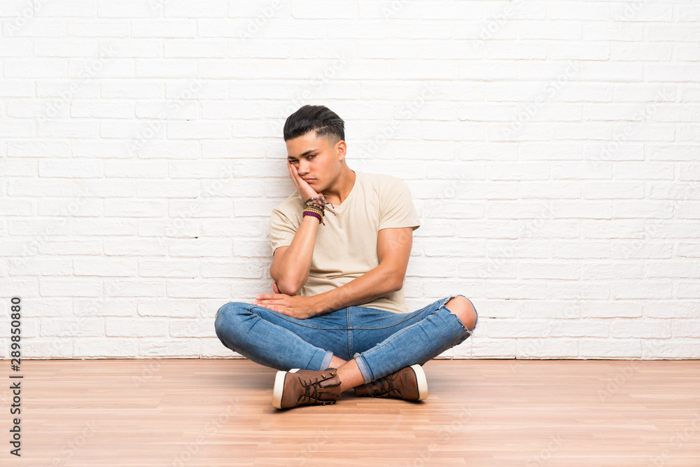 Young man sitting on the floor unhappy and frustrated Young man sitting on the floor unhappy and frustrated