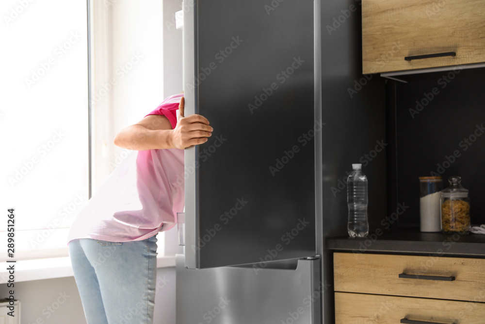 Woman looking into refrigerator full of products in kitchen Woman looking into refrigerator full of products in kitchen