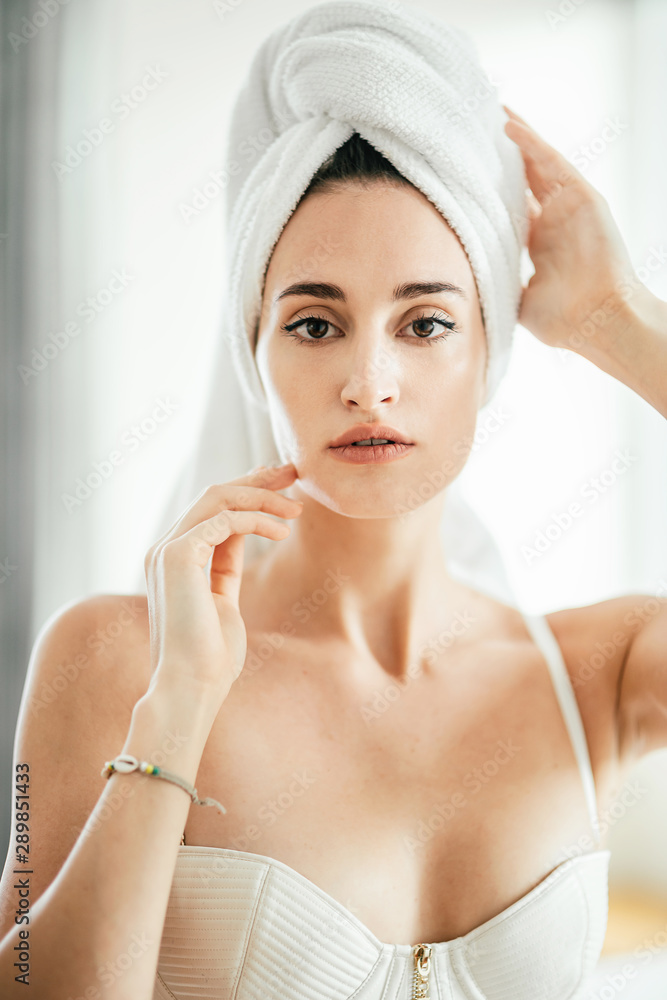 Portrait of beautiful caucasian girl in lingerie with towel on her head looking at the camera while standing in bedroom in the morning. Vertical shot Portrait of beautiful caucasian girl in lingerie with towel on her head looking at the camera while standing in bedroom in the morning. Vertical shot