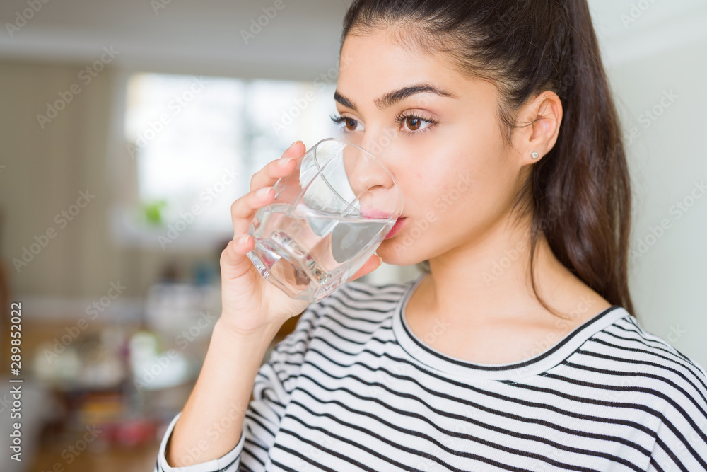 Beautiful young woman drinking a fresh glass of water at home Beautiful young woman drinking a fresh glass of water at home
