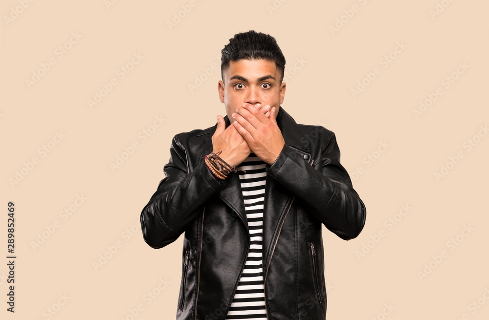 Young man covering mouth with hands over isolated background Young man covering mouth with hands over isolated background
