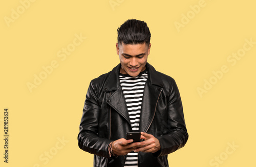 Young man sending a message with the mobile over isolated background © luismolinero